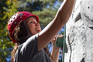 Happy woman climbing rock face